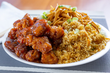 A view of a combo plate of a Chinese fast food restaurant, featuring orange chicken, chow mein and...