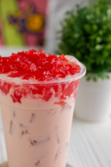 A closeup view of a milk tea with strawberry jelly toppings.