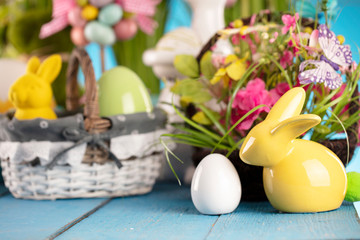 Easter theme. Easter decorations. Easter eggs in basket and cabbage leaf. Bouquet of spring flowers. Blue background.