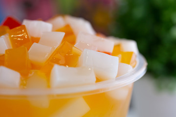 A closeup view of colorful jelly toppings on top of an Asian boba beverage in a restaurant or kitchen setting.