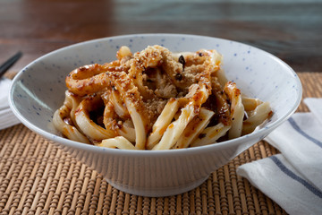 A view of a plate of Chinese thick noodle, in a restaurant or kitchen setting.