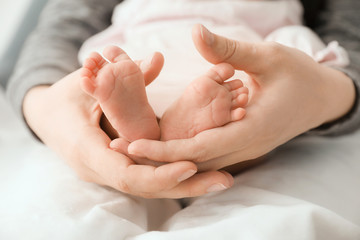Mother's holding tiny feet of little baby, closeup