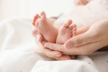 Obraz na płótnie Canvas Mother's holding tiny feet of little baby, closeup