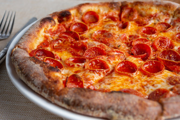 A closeup view of a rustic pepperoni pizza in a restaurant or kitchen setting.