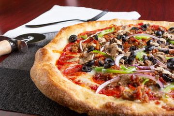 A view of a meat and veggie pizza pie, in a restaurant or kitchen setting.