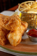 A view of a plate of fish and chips in a restaurant or kitchen setting.