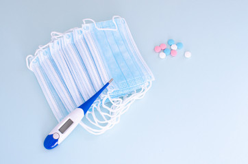 Many Medical mask, Medical protective mask on blue background with pills and thermometer. Disposable surgical face mask cover the mouth and nose. Healthcare and medical concept.