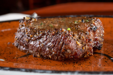 A closeup view of a top sirloin steak on a plate in a restaurant or kitchen setting.