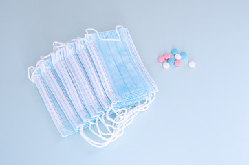 Many Medical mask, Medical protective mask on blue background with Multi-colored tablets. Disposable surgical face mask cover the mouth and nose. Healthcare and medical concept.
