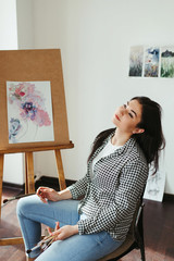 Art, creativity, professional occupation. Artist at work in home studio. Woman painting with watercolor at easel. Creative leisure concept