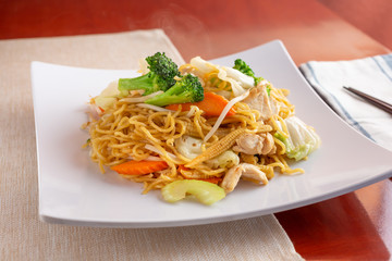 A view of a plate of chow mein on display in a restaurant or kitchen setting.