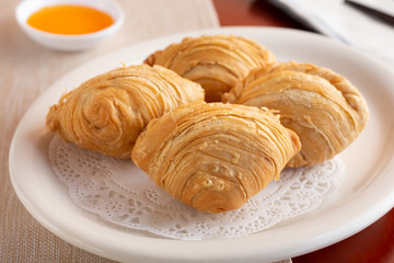 A view of a plate of Thai baked curry puff in a restaurant setting, part of several dishes on a dinner table.