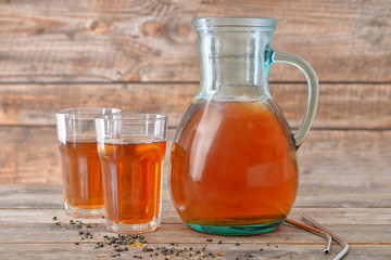 Jug and glasses of tasty cold tea on wooden table