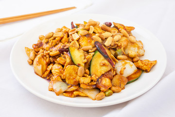 A view of a Chinese plate of kung pao chicken, in a restaurant or kitchen setting.