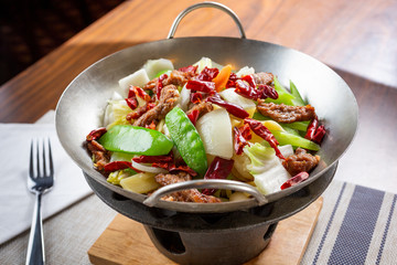 A view of a wok with an entree of spicy beef and steamed vegetables.