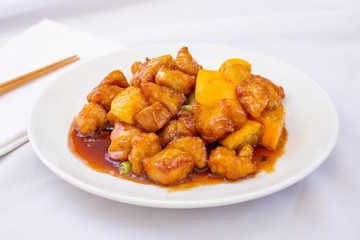 A view of a plate of Chinese orange chicken, in a restaurant or kitchen setting.