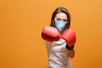 woman in boxing gloves, home quarantine, coronavirus pandemic, on yellow orange background, battle fight with virus