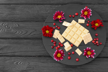 Sweet white chocolate with cranberry and flowers on table