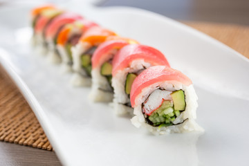 A closeup view of a rainbow roll sushi plate, in a restaurant or kitchen setting. © DAVID