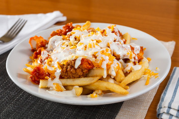 A view of a plate of loaded fries in a restaurant or kitchen setting.