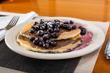 A view of a plate of blueberry pancakes in a restaurant or kitchen setting.