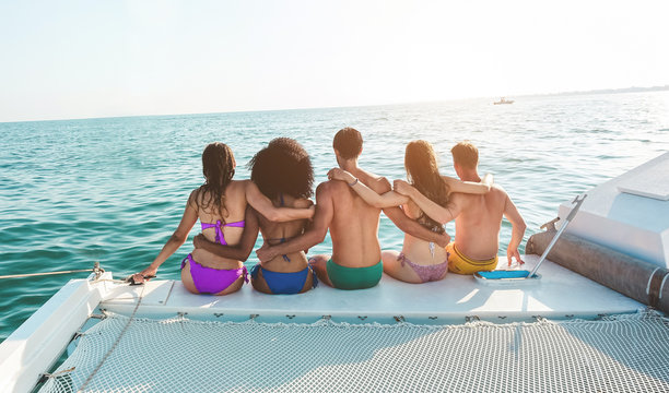 Young friends chilling in catamaran boat - Group of people making tour ocean trip - Travel, summer, friendship, tropical concept - Focus on center man's head