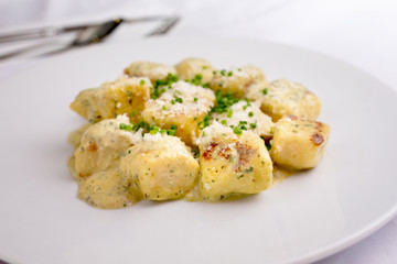 A closeup view of a plate of gnocchi, in a restaurant or kitchen setting.
