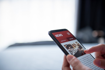 Online news on a smartphone. (Mockup website). Woman reading news or articles in a mobile phone screen application at home. Newspaper and portal on internet, copy space.