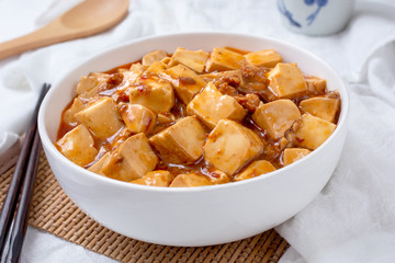 A view of a bowl of mapo tofu, in a restaurant or kitchen setting.