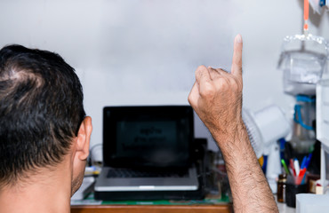 Work form home alone,Man showing little finger and promised to stay at home against laptop background at his home. Stop covid-19 or slow down the spread of disease,the virus crisis,pubiic mind.