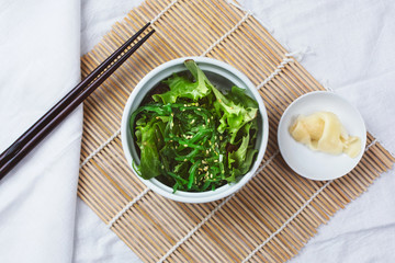 A top down view of a wakame salad, in a restaurant or kitchen setting.