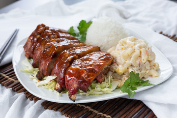 A view of a plate of Hawaiian style barbecue ribs, in a restaurant or kitchen setting.
