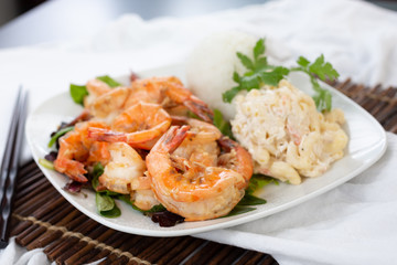 A view of a plate of garlic prawns, in a restaurant or kitchen setting.