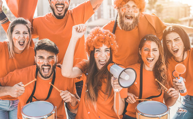 Fototapeta Orange sport fans screaming while supporting their team - Football people supporters having fun at competion event - Champions, betting and winning concept - Focus on center girl face obraz