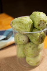 A view of a container full of green cactus pears in a restaurant or kitchen setting.