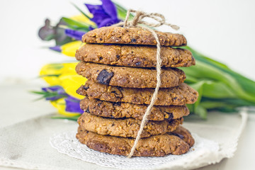 American cookies with chocolate are laid out stacked one on one on a light table near flowers. The concept of homemade cakes for the holiday. Culinary background, copy space