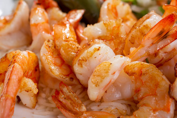 A closeup view of several cooked butterfly cut shrimp.