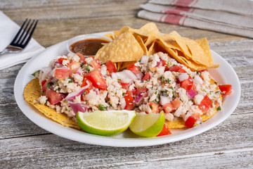 A view of a plate of fish ceviche tostadas, in a restaurant or kitchen setting.