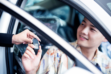 Sellers or car salespeople and customers in the dealership provide car keys and seal the purchase of new cars or cars.