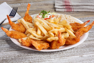 A view of a plate of deep fried shrimp with a side of french fries, in a restaurant or kitchen setting.