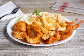A view of a plate of deep fried shrimp with a side of french fries, in a restaurant or kitchen setting.