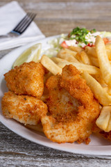 A closeup view of a deep fried shrimp plate, with a side of french fries, in a restaurant or kitchen setting.