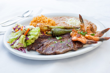 A view of a plate of Mexican surf and turf, in a restaurant or kitchen setting.