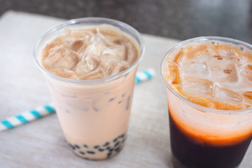 A view of a two drinks in a restaurant or kitchen setting, featuring Vietnamese coffee with boba, and Thai Tea.