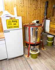 extracting honey, honey flowing out of centrifuge into a sieve hanging in a bucket