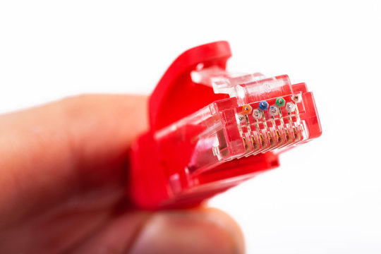 8P8C, RJ-45 crimped red ethernet modular connector, unshielded twisted pair UTP internet cable end in hand, macro, detail, closeup. Individual cables visible. Cable crimping simple concept, isolated