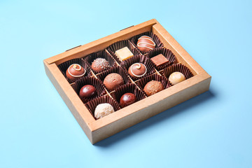 Box with delicious chocolate candies on color background