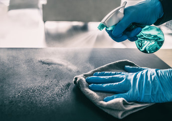 Surface sanitizing against COVID-19 outbreak. Home cleaning spraying antibacterial spray bottle disinfecting against coronavirus wearing nitrile gloves. Sanitize hospital surfaces prevention. - obrazy, fototapety, plakaty