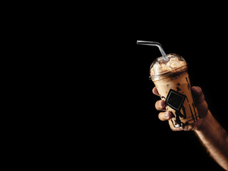Naklejka premium Chocolate frappe coffee with whipped cream and syrup on dark background in men hand