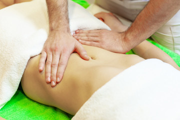 Fototapeta na wymiar Top view of hands massaging female abdomen. Therapist applying pressure on belly. Woman receiving massage at spa salon